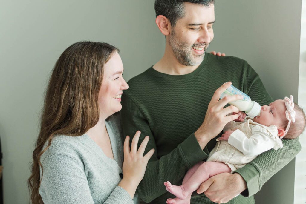 Mom and dad hold baby during their Louisville in-home newborn session.