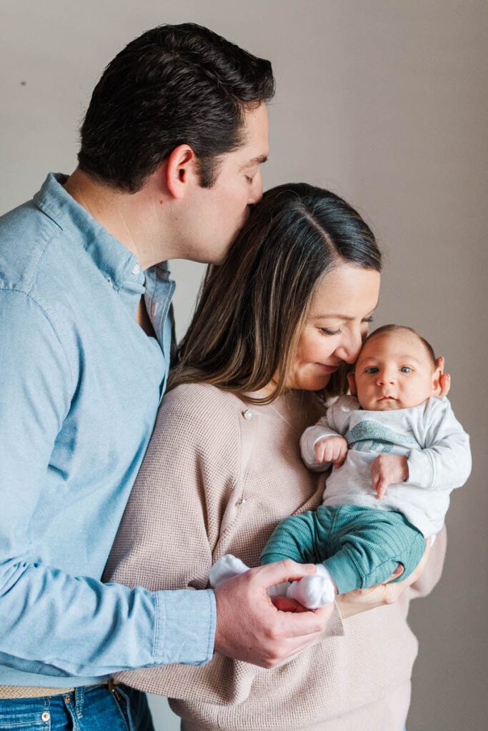 Mom and dad hold baby during their Louisville in-home newborn session.