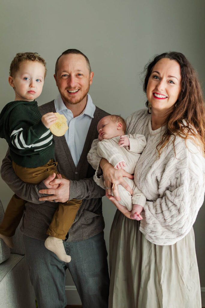 Family smiles for photo during their Louisville in-home newborn session.