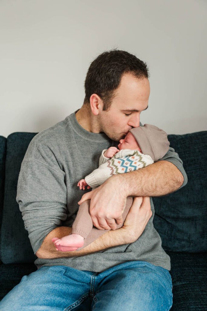 A new dad kisses baby boy on the head.