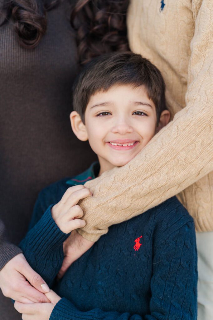 A boy smiles at the camera during a winter family session. Photos by Michelle Bordenkircher Photography