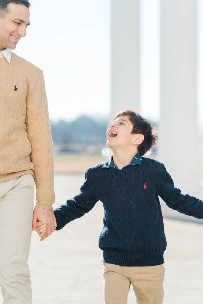 A young boy smiles playfully at his dad during their family session Photos by Michelle Bordenkircher Photography
