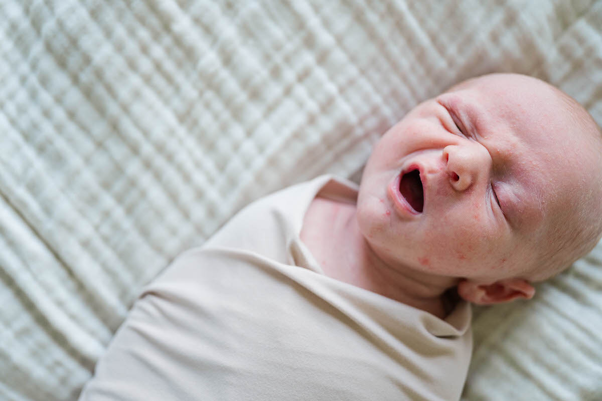 A baby boy yawns during his Louisville In-Home newborn session Photos by Michelle Bordenkircher Photography
