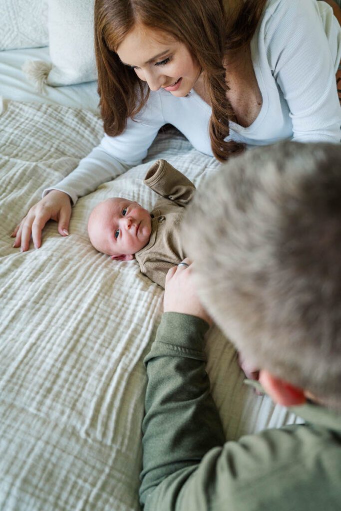 A mom and dad smiling at their new baby during their Louisville In-Home newborn session Photos by Michelle Bordenkircher Photography
