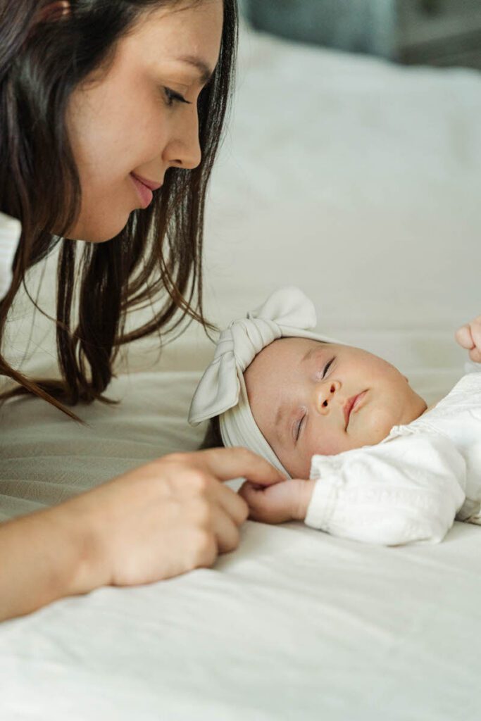 A mom gently holds her newborn baby's hand during a Louisville In-Home Family Photography Session. Photos by Michelle Bordenkircher Photography.
