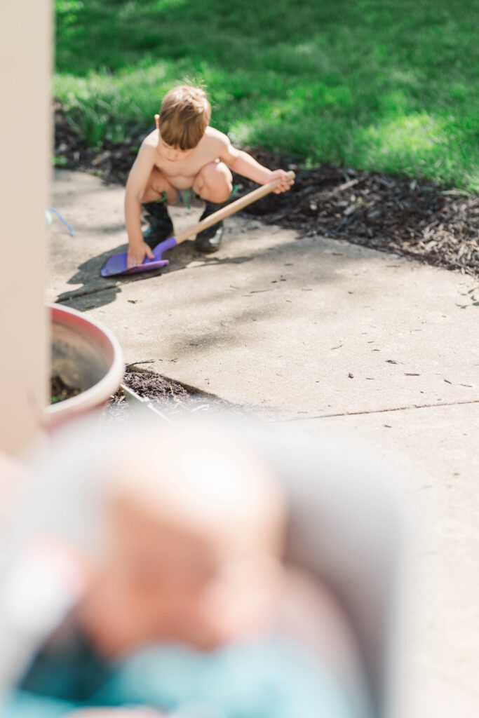 A little one enjoys playing in his space outdoors during a Louisville In-Home Family Photographer Photos By Michelle Bordenkircher Photography